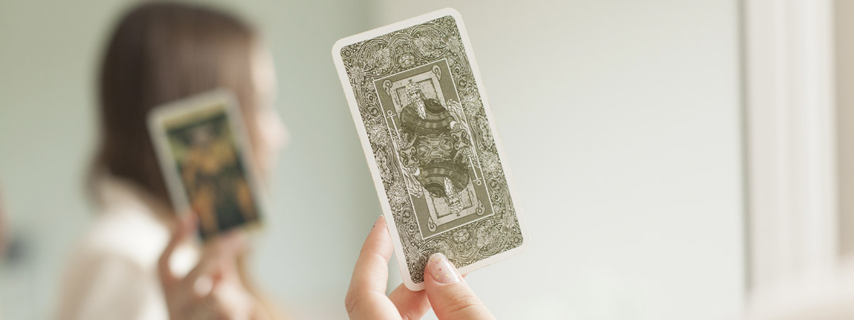 Mujer sosteniendo cartas del Tarot Rider-Waite frente a un espejo
