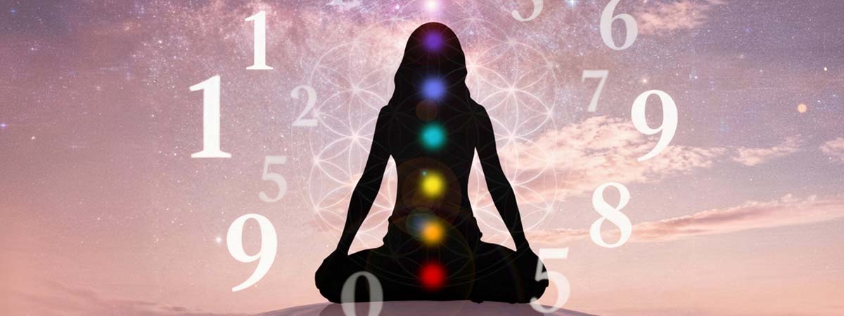 Silueta en meditación con los 7 chakras iluminados rodeada de números flotantes sobre fondo cósmico rosado