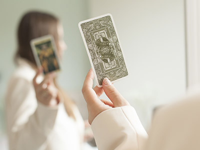 Mujer sosteniendo cartas del Tarot Rider-Waite frente a un espejo