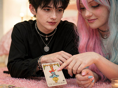 Pareja joven consultando una carta del tarot invertida juntos, ambiente íntimo con velas
