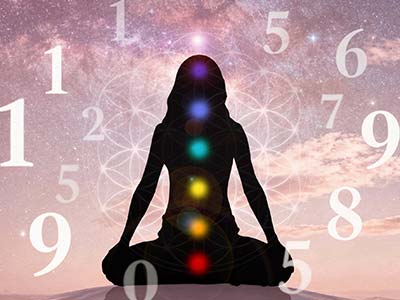 Silueta en meditación con los 7 chakras iluminados rodeada de números flotantes sobre fondo cósmico rosado