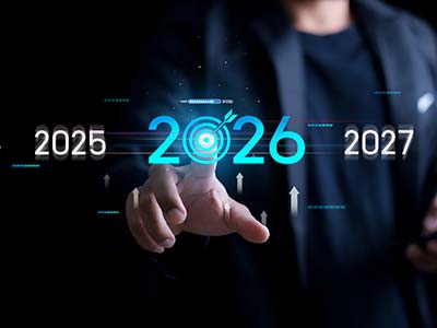 Businessman pointing at illuminated blue 2026 with upward arrows on dark background, representing business goals